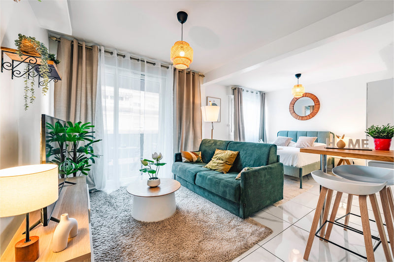 Séjour avec canapé vert, coin repas et suspension tressée, appartement à Annemasse