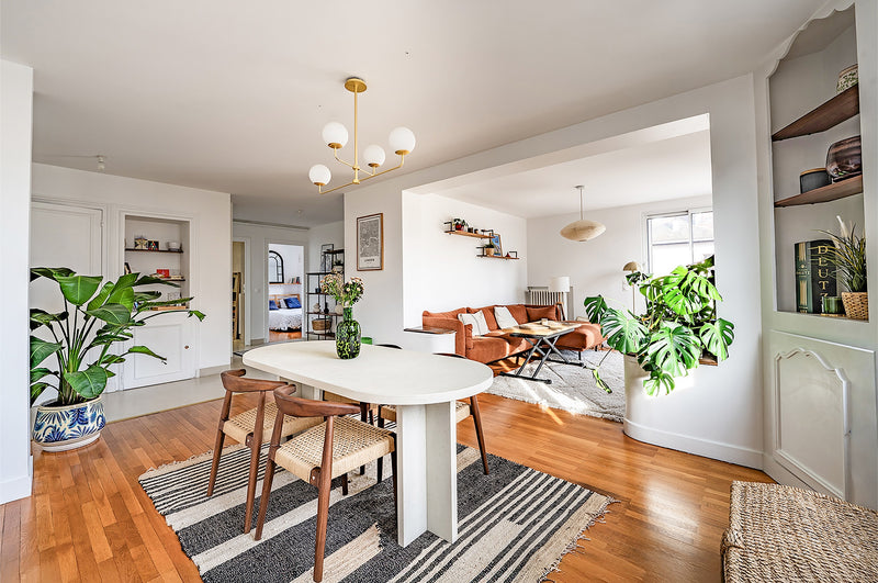 Séjour lumineux avec table ovale blanche, plantes et parquet, appartement à Annecy